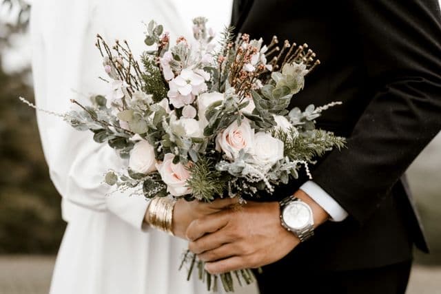 Hands holding a white wedding bouquet
